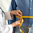 Doctor measuring waist of patient.