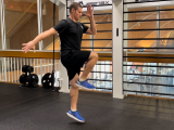 Trainer performing cycle jump in gym