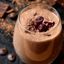 Glass of Chocolate Cherry smoothie next to cherries and chocolate pieces 