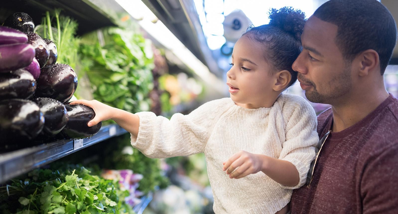 A young kids grocery shopping with an adult