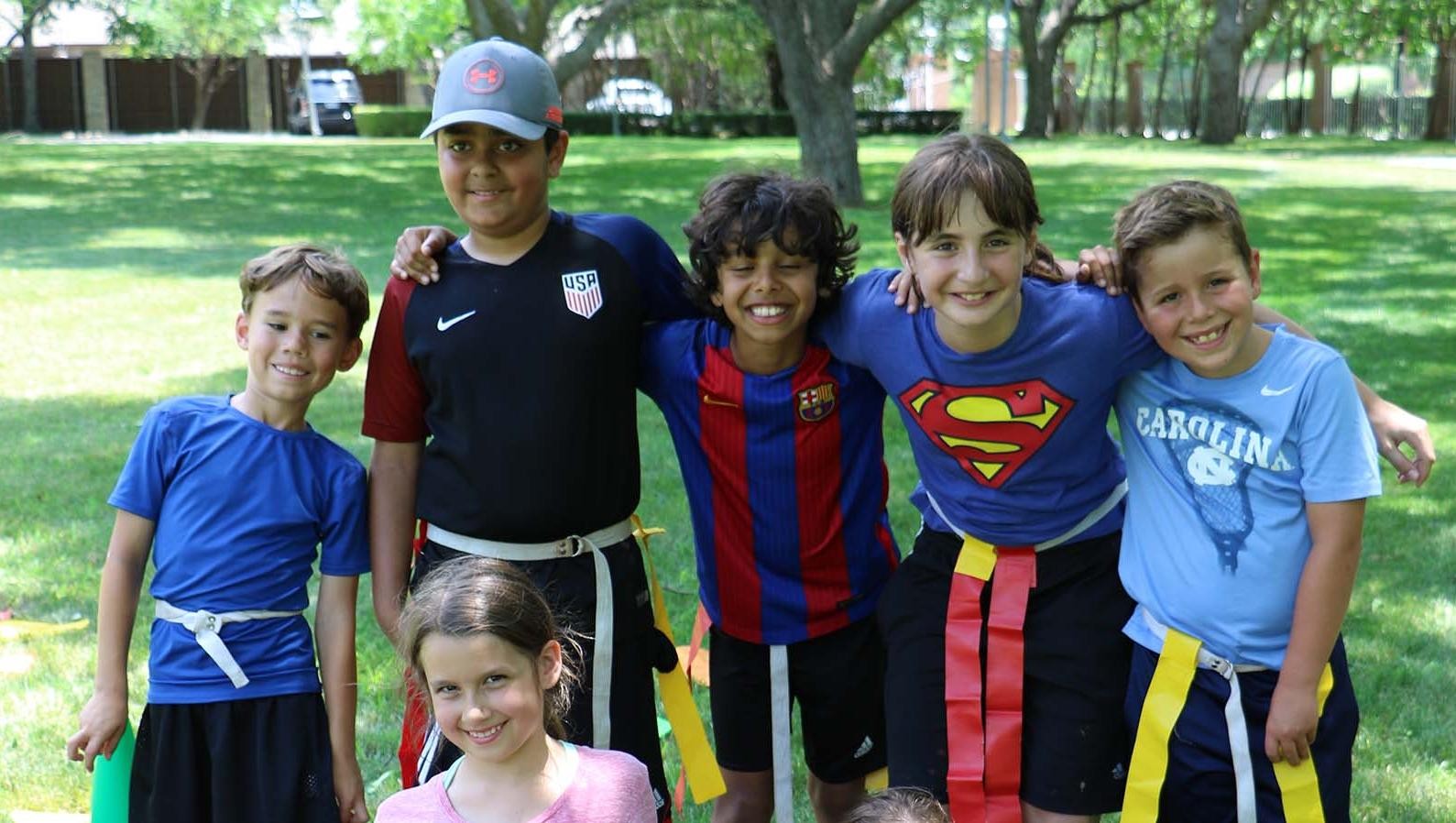 Camps - 5 kids posing as a group outdoors at camp
