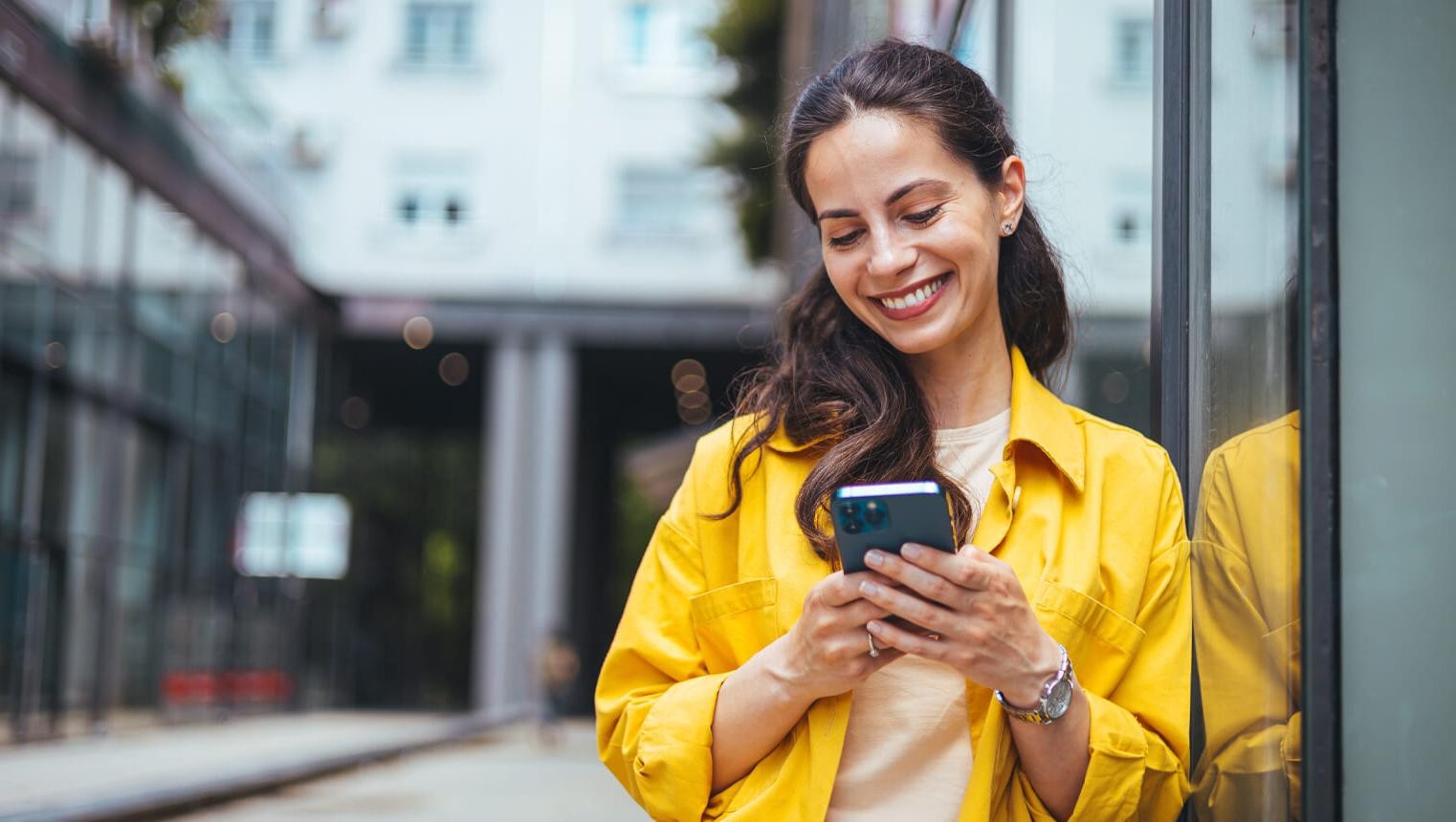 Female business professional walking outside and texting from her mobile phone