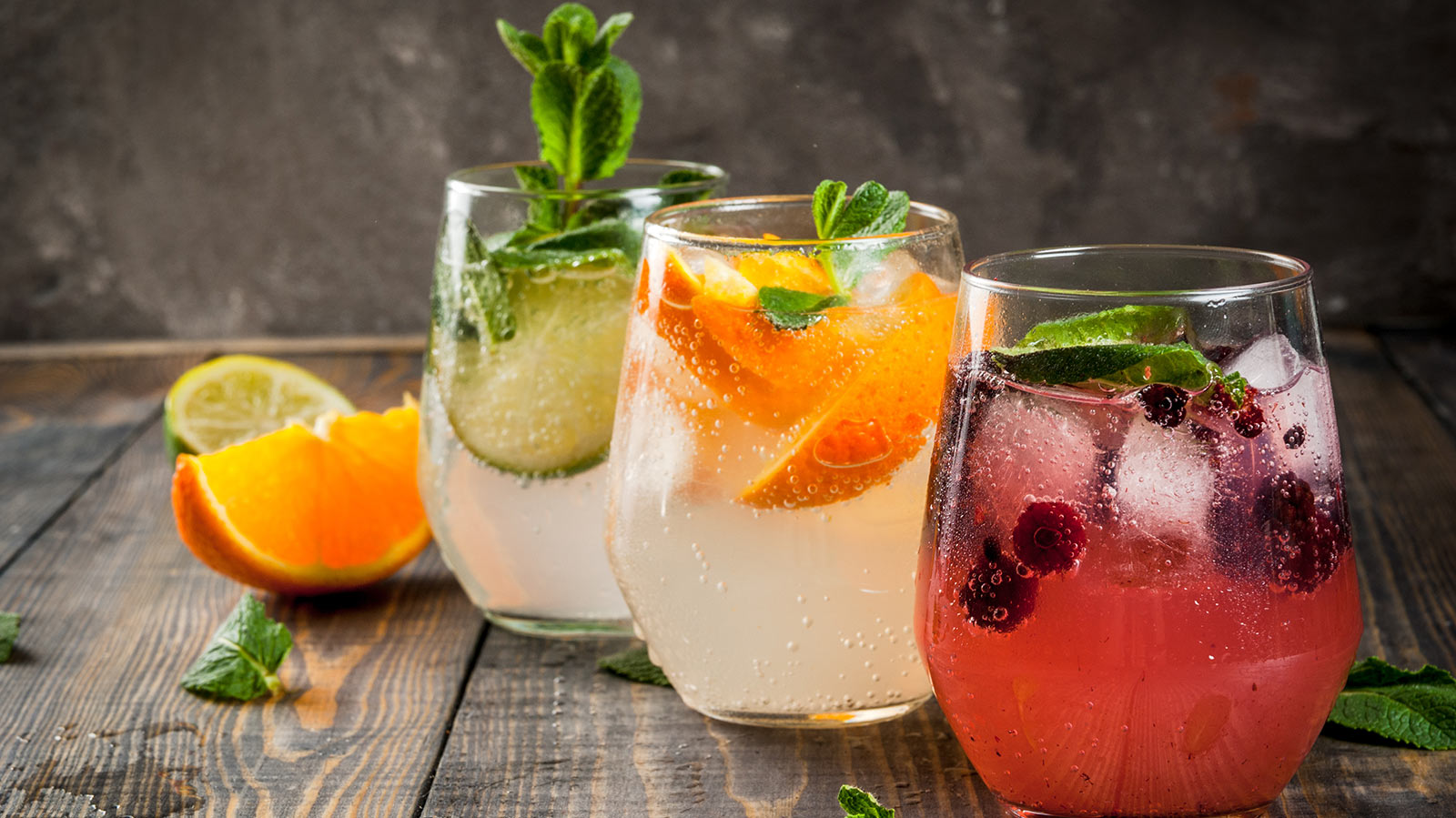 Selection of three kinds of gin tonic: with blackberries, with orange, with lime and mint leaves.