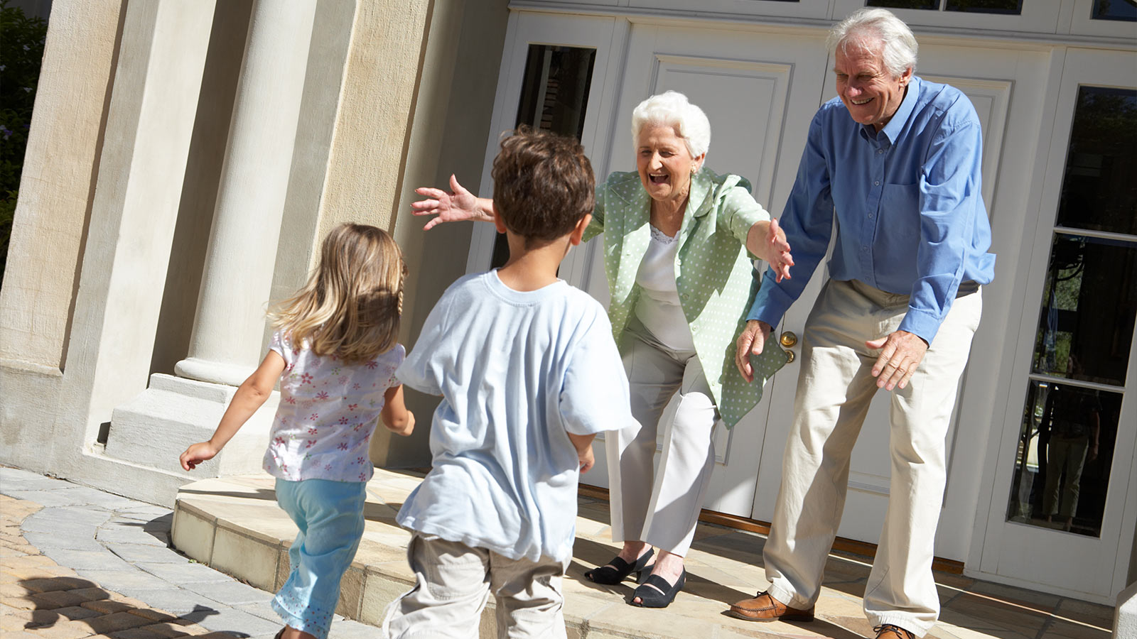 2 healthy aging couple happy with the kids running towards them