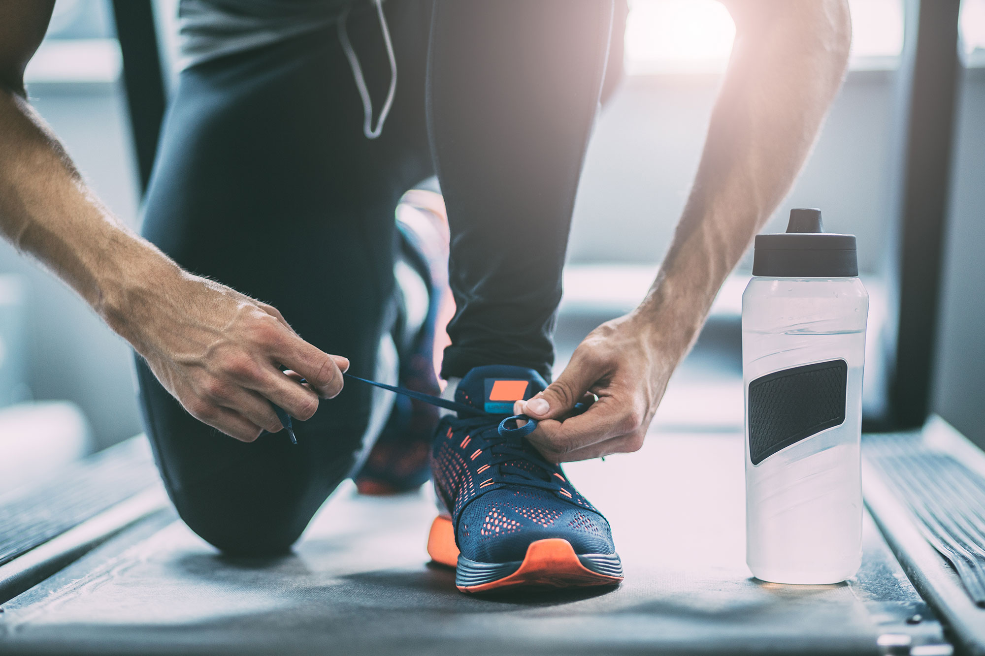 Man tying shoe on treadmill