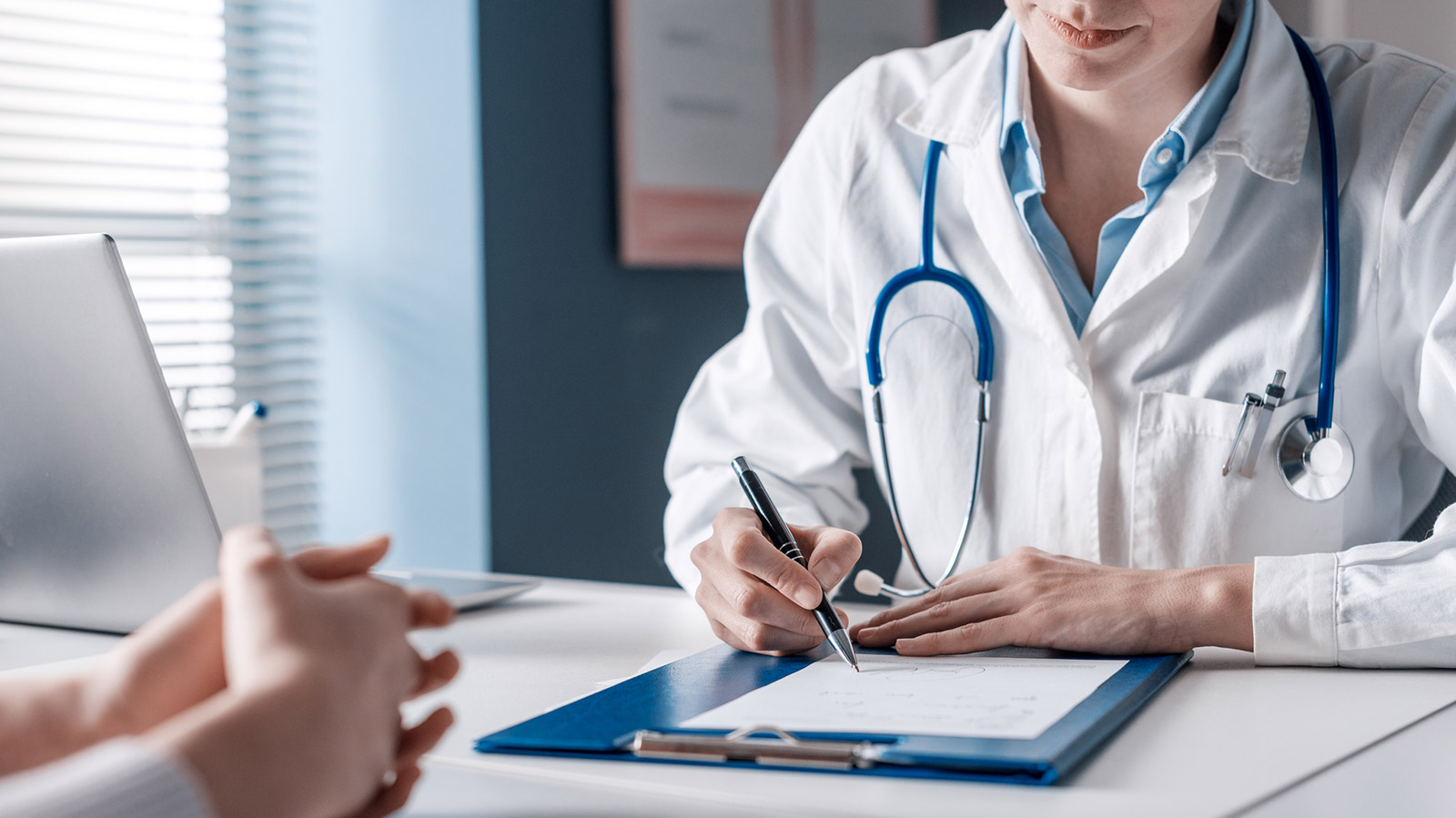 Doctor sitting at desk and writing a prescription for her patient