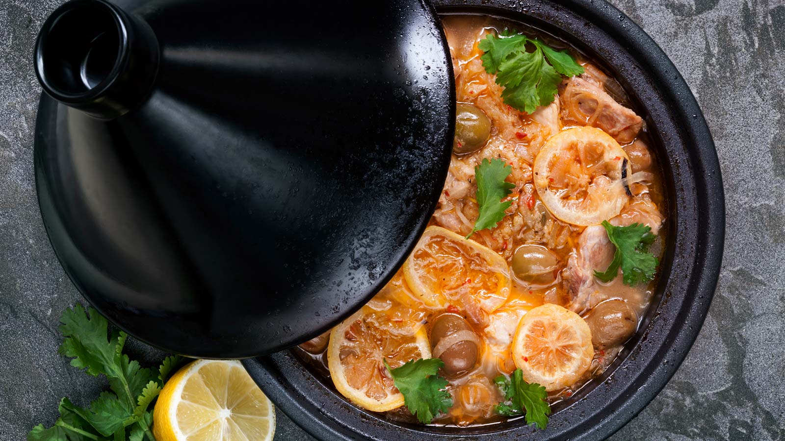 Chicken cooking in traditional tagine. With lemons, green olives and cilantro.
