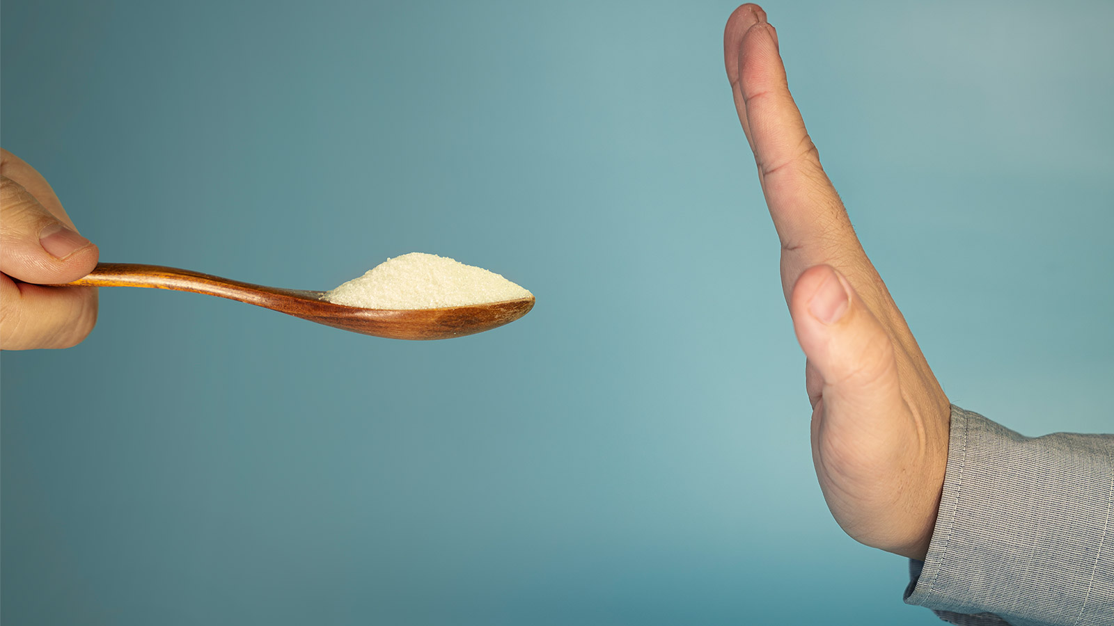 A hand saying no to a spoon full of sugar