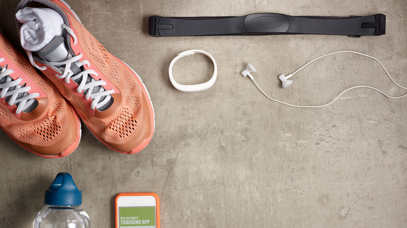 Image of overshot of shoes, water bottles, fitness tracker, iphone and ear phones