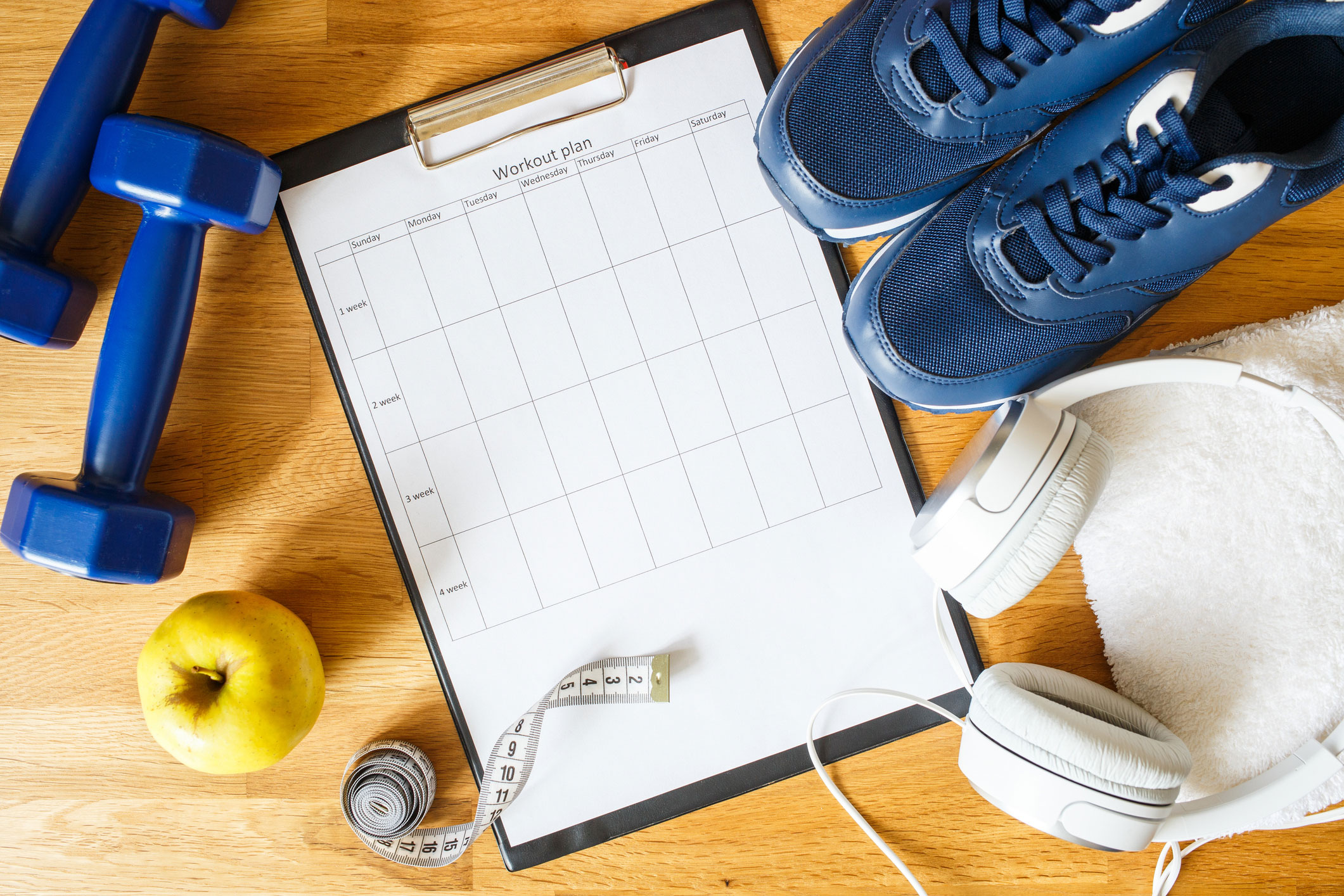 Workout log with handweights, measuring tape, athletic shoes and headphones