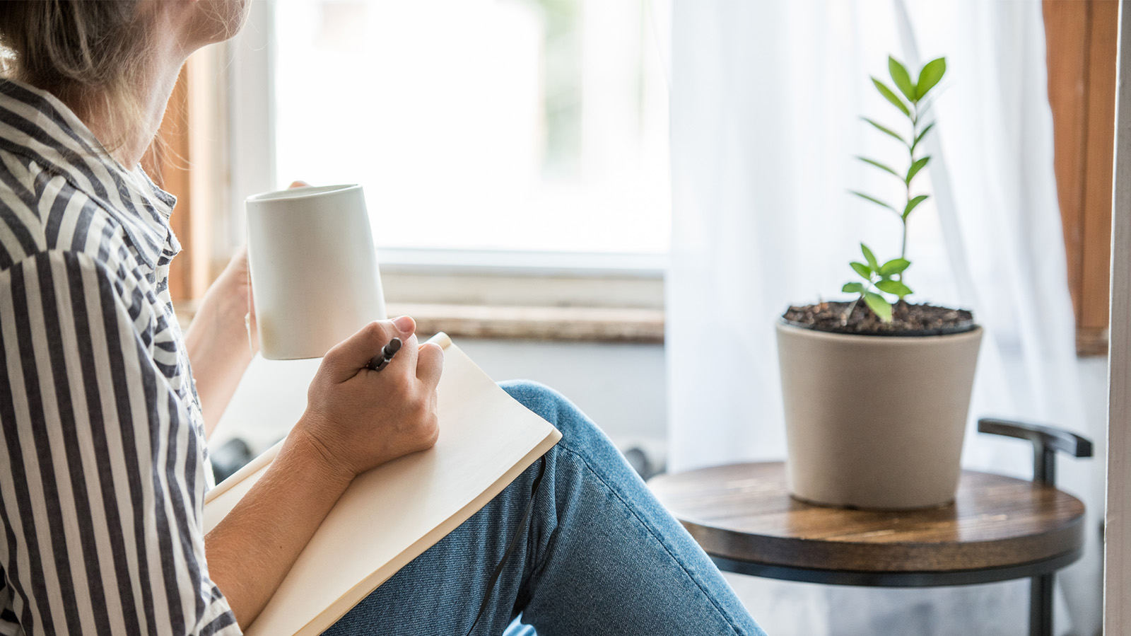 Woman writing with coffee in a notepad