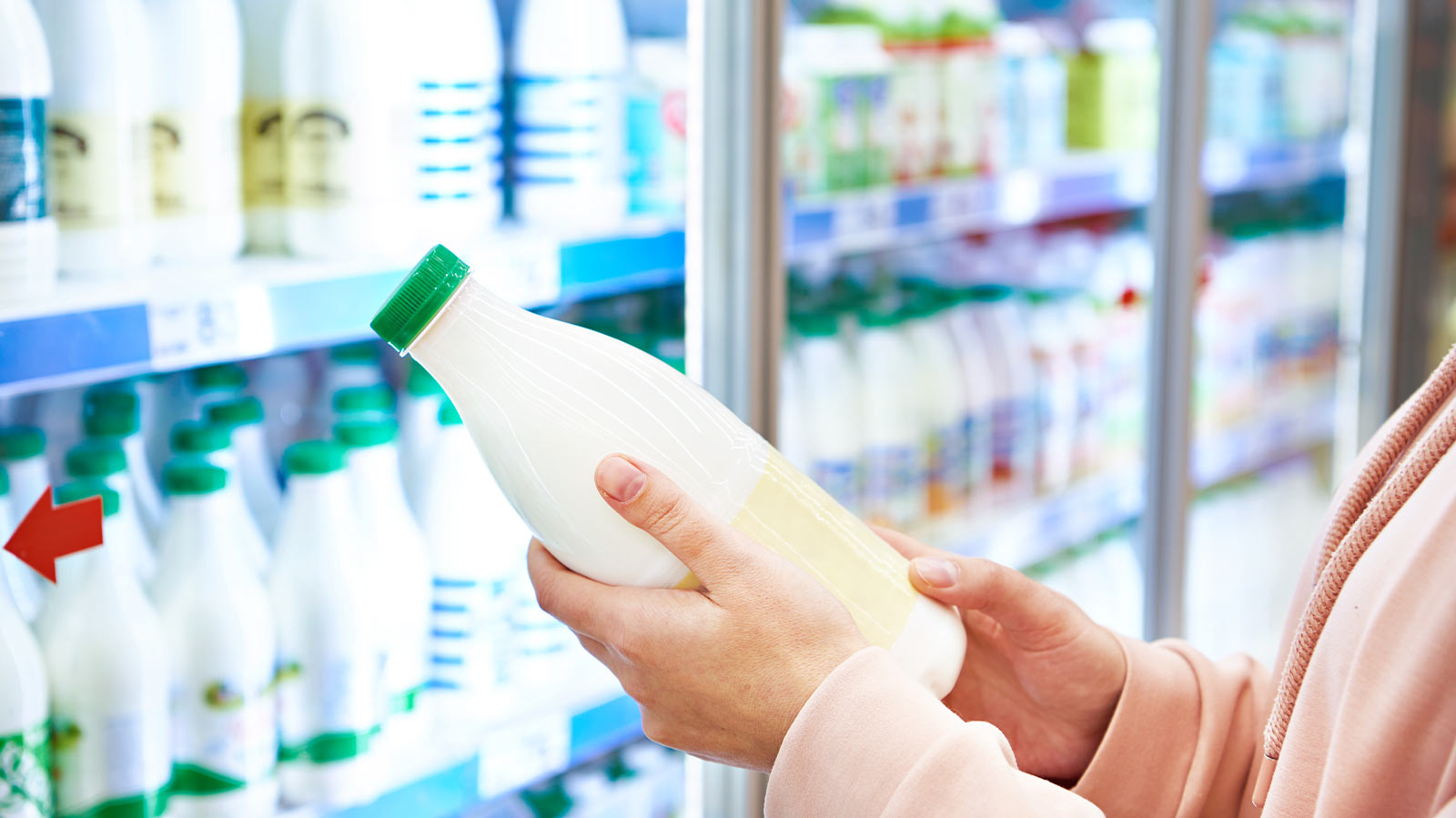 A woman in a grocery store examining a bottle of milk