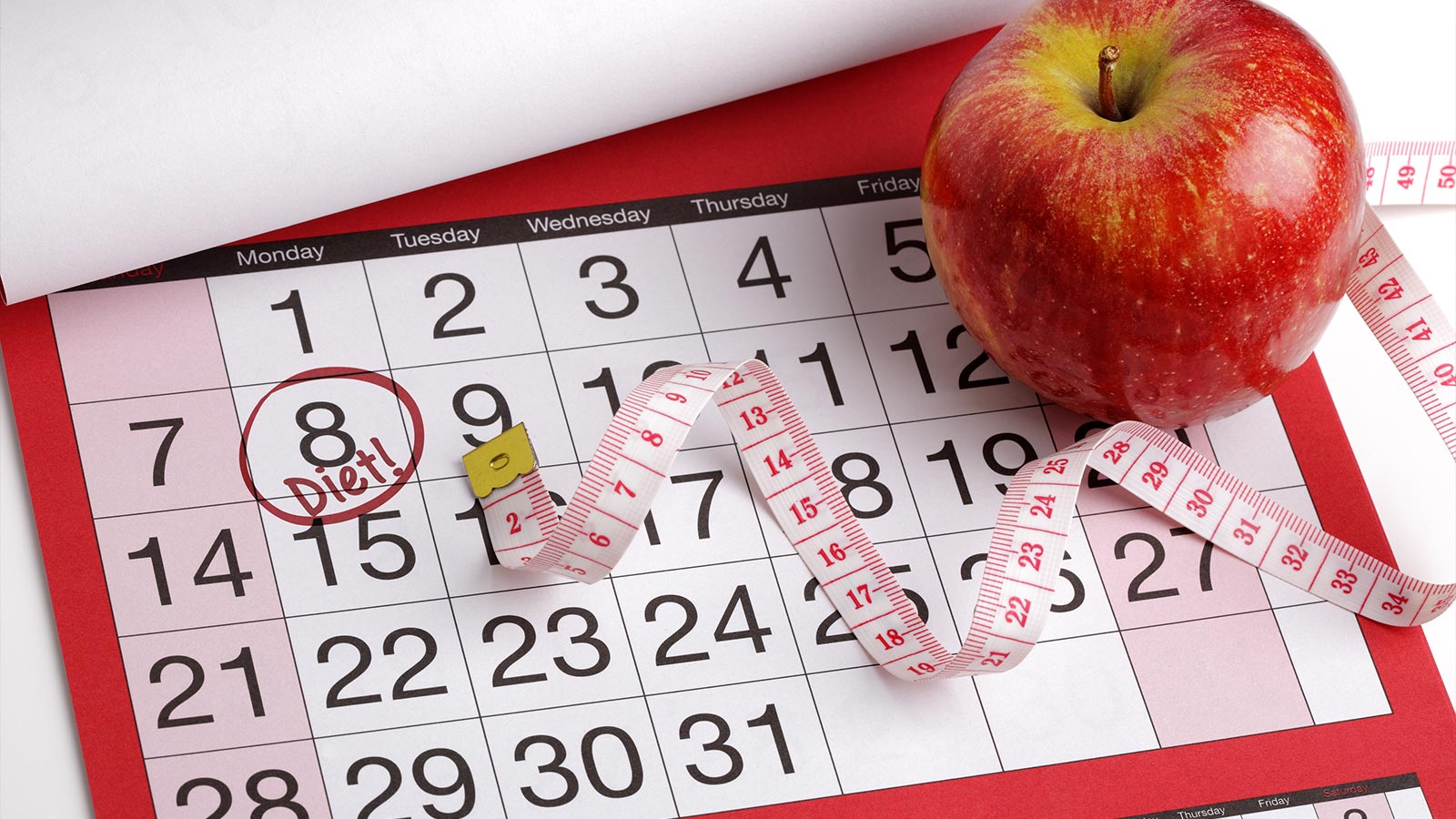Dieting concept apple and tape measure on a calendar with a date to start a diet