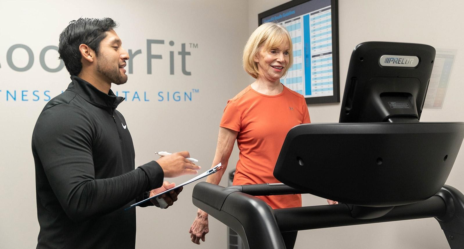 CooperFit Coach helping instruct a woman in an orange shirt