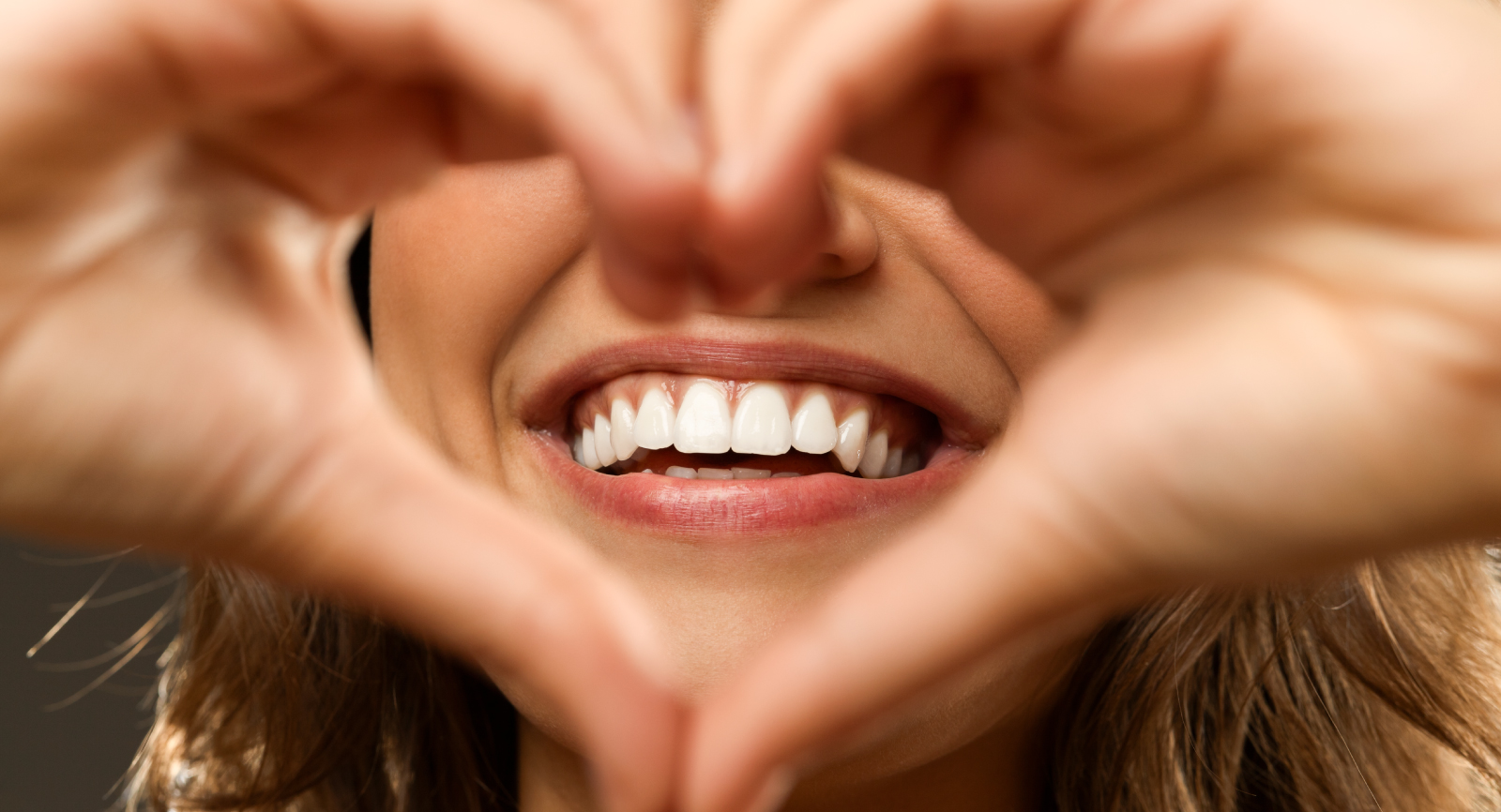 Woman smiling with hands forming a heart shape