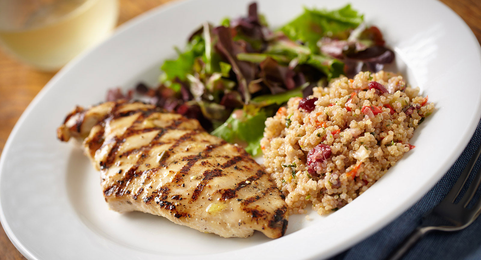 Chicken, quinoa, and salad on a white plate