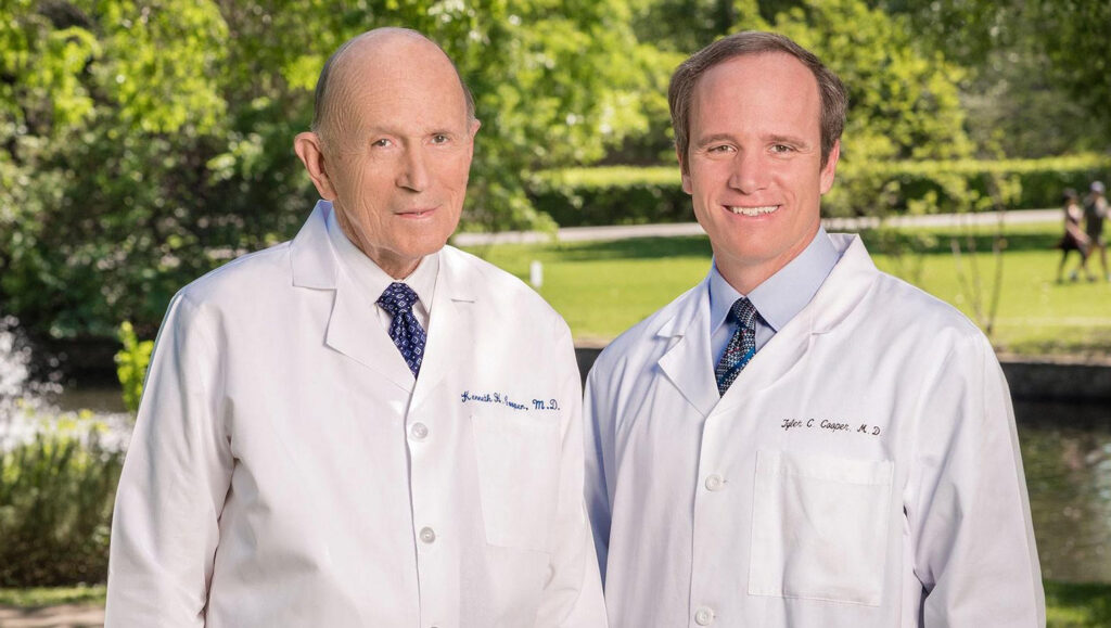 Dr. Kenneth Cooper and Dr. Tyler Cooper standing by trees